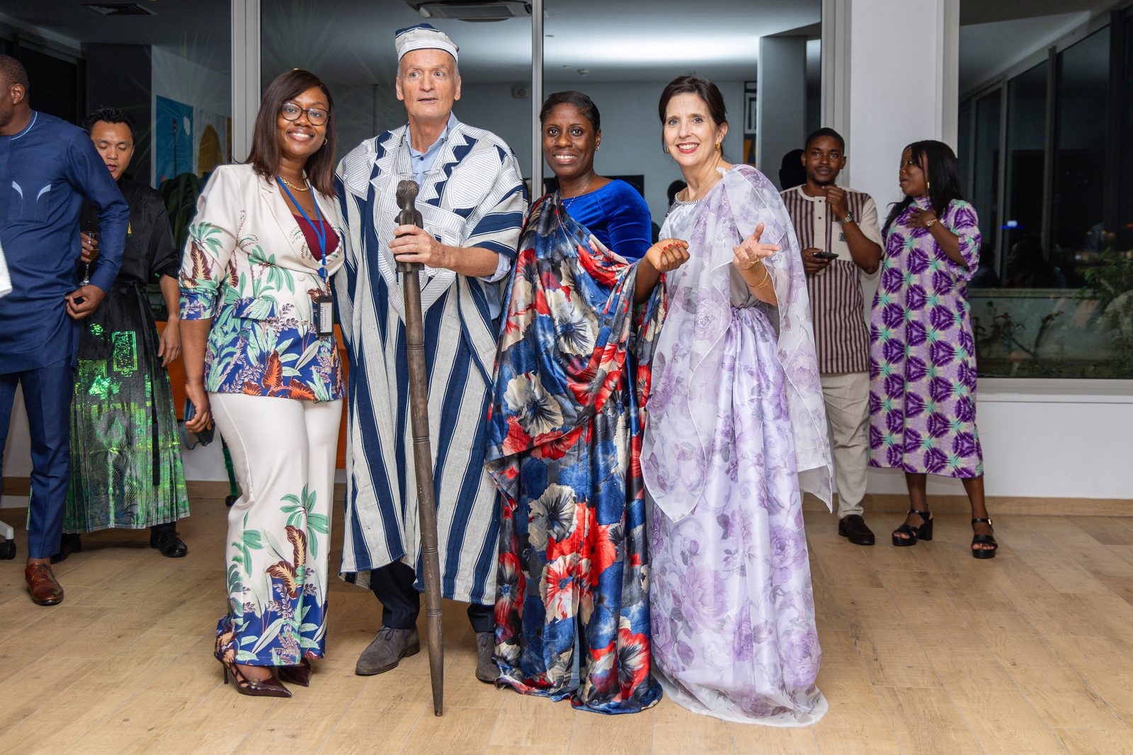 Quatre invités en tenues traditionnelles posent ensemble, l'un tenant une canne sculptée