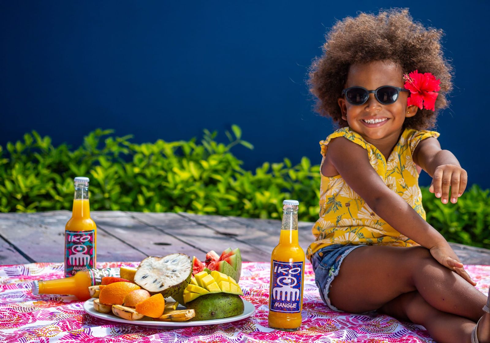 Une petite fille à lunettes de soleil tend une bouteille de jus